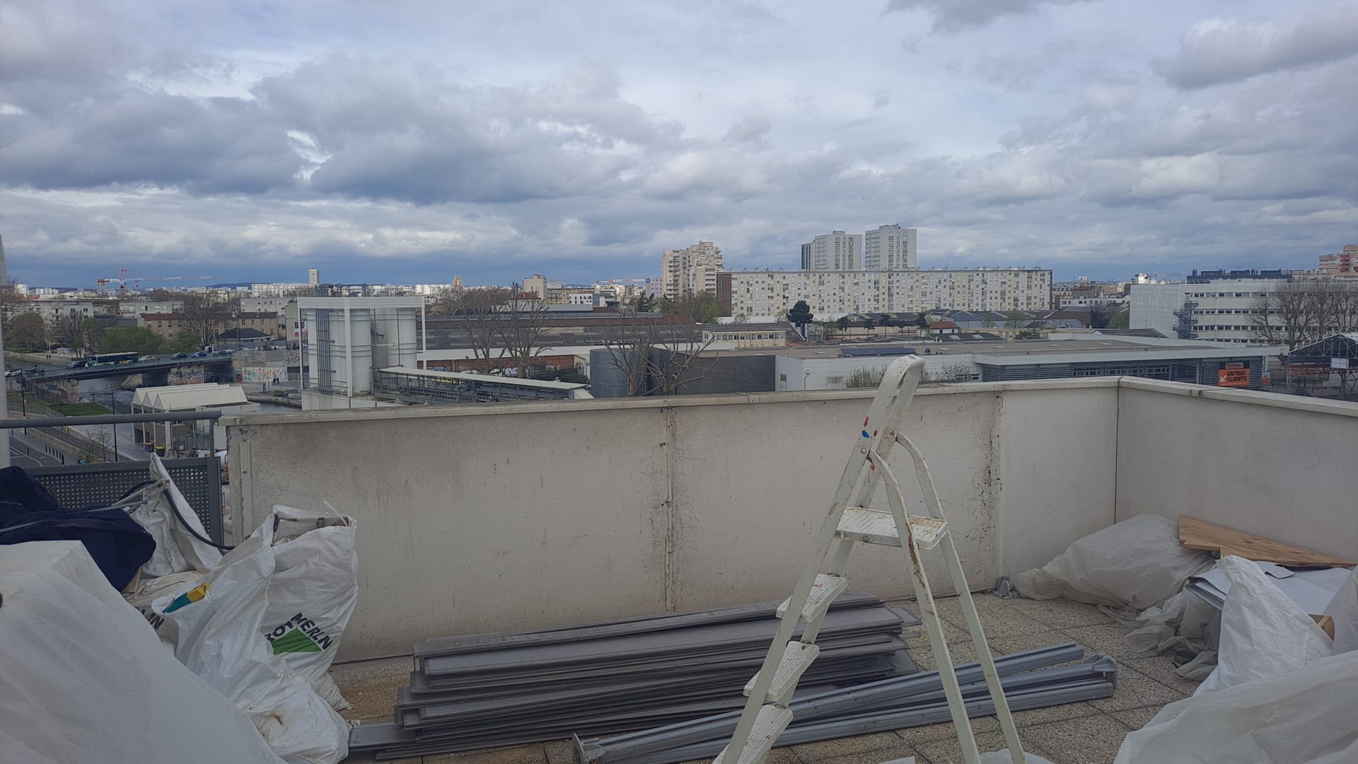 Terrasse en chantier : gravats, échafaudage, matériaux de construction, vue sur Aubervilliers