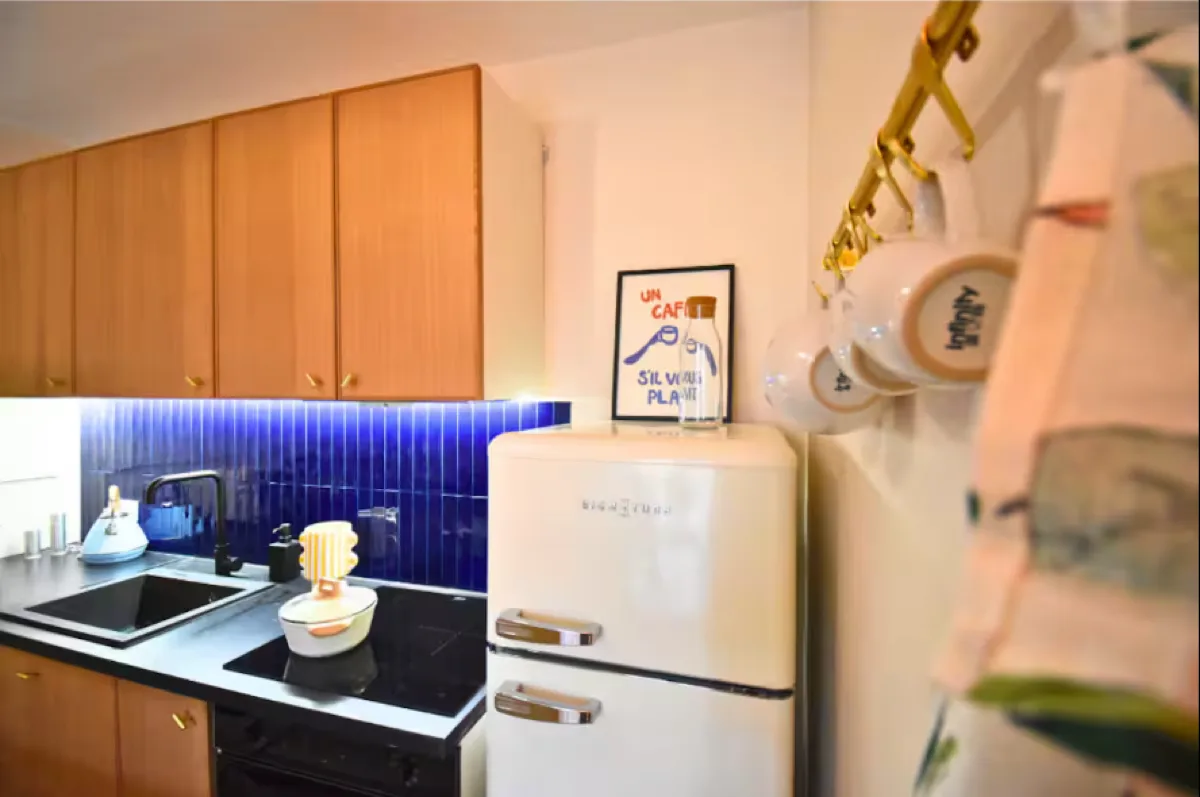 Côté rangements de la cuisine : ustensiles suspendus, crédence bleue éclairée, organisation apparente