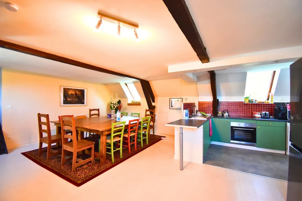 Loft après : grande table en bois massif 10 couverts, chaises colorées, cuisine verte avec carrelage rouge