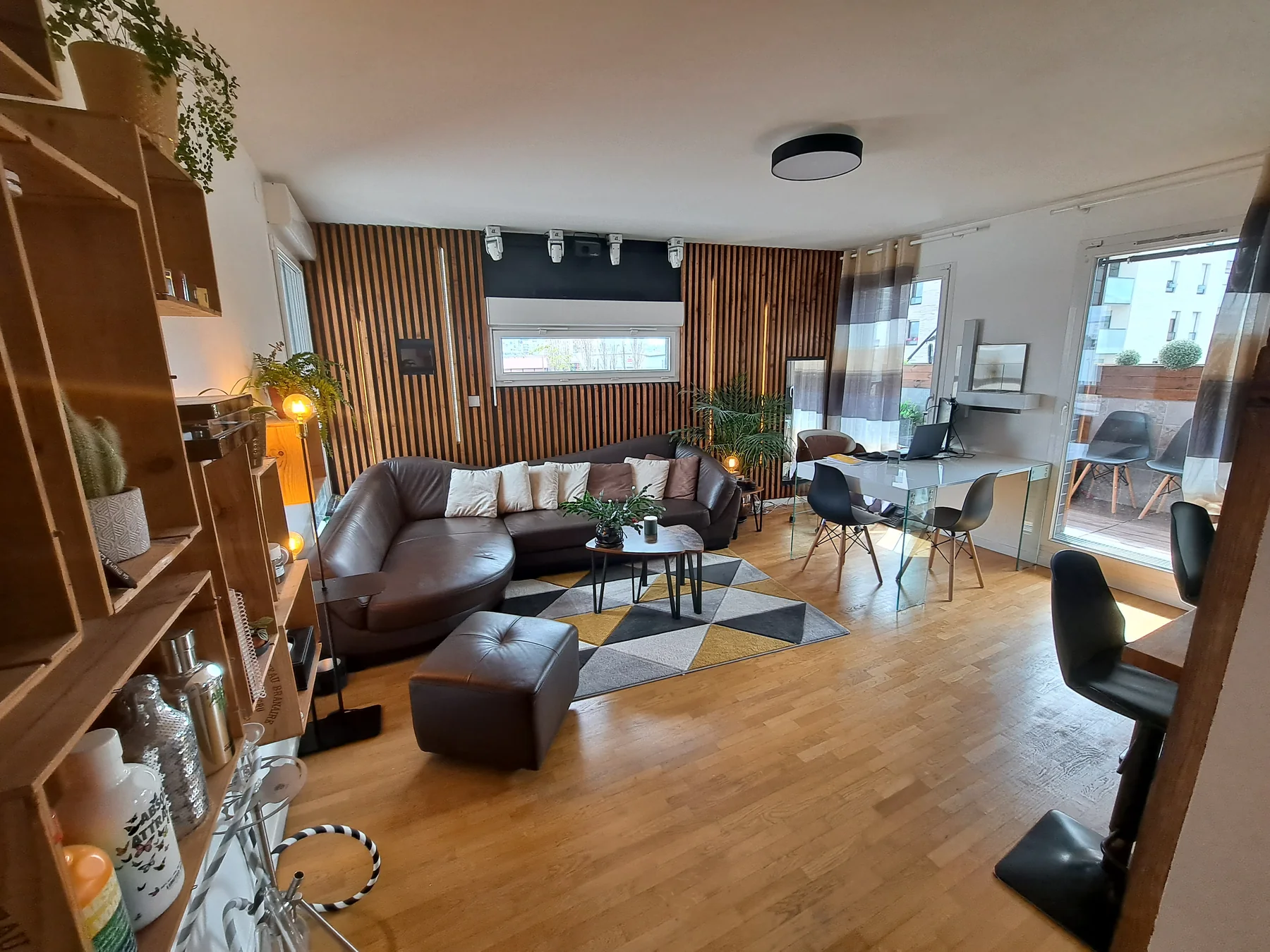 Salon après rénovation : canapé, coin repas, claustra bois, plantes et décoration chaleureuse